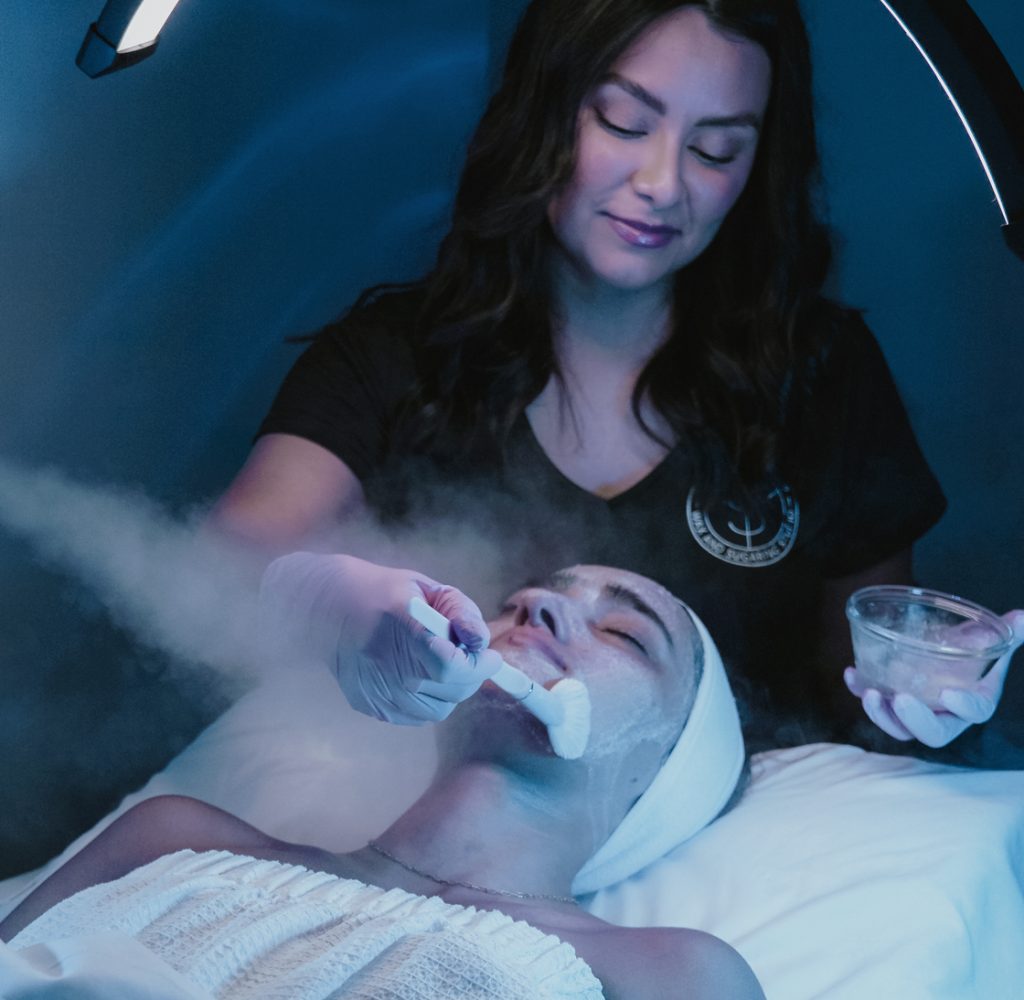 Esthetician caring for a client during a facial at The Landing Strip Studio